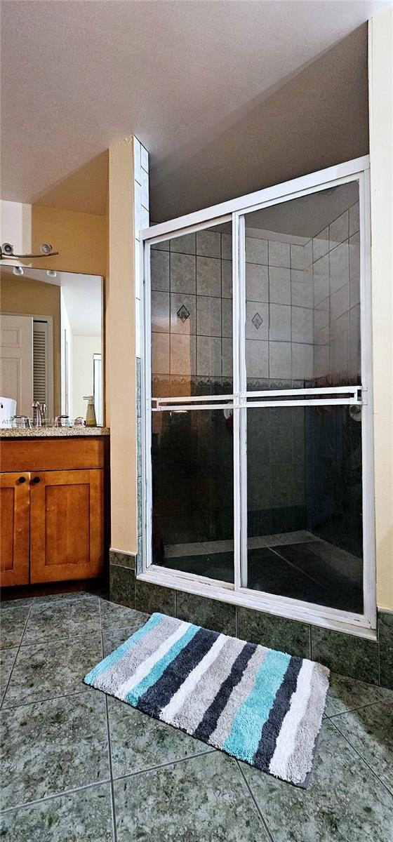 full bathroom with a stall shower, vanity, and tile patterned floors