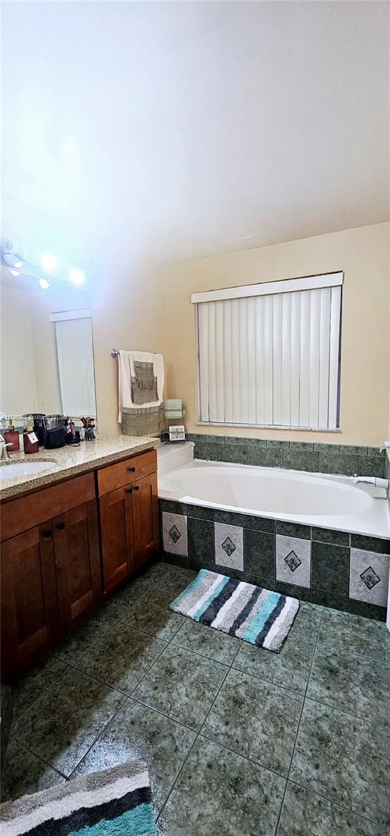 bathroom with a garden tub, vanity, and tile patterned floors