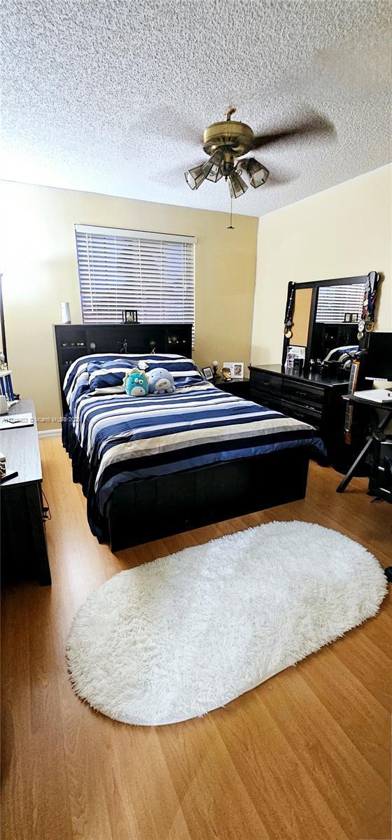 bedroom featuring a ceiling fan, a textured ceiling, and wood finished floors