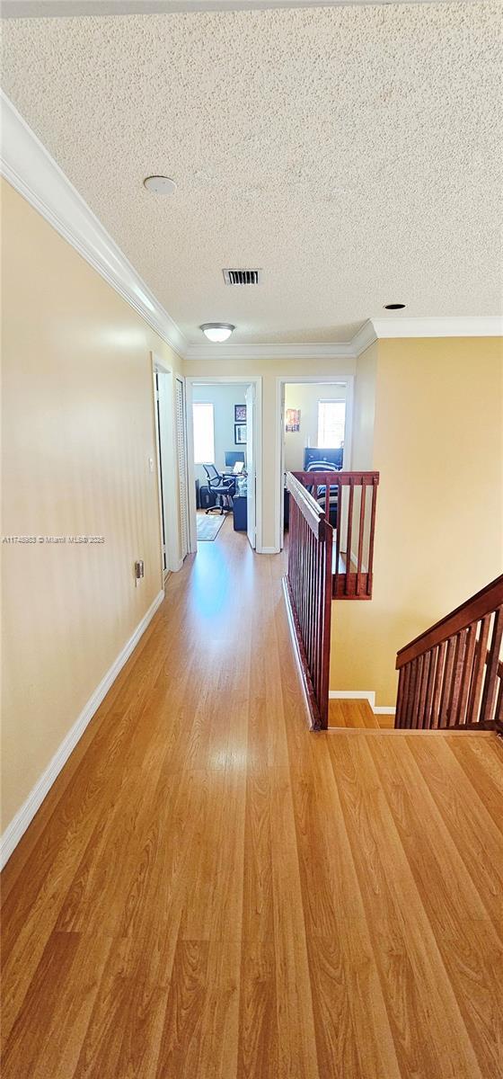 18860 NW 12th St, Pembroke Pines, FL 33029 - hall with an upstairs landing, crown molding, light wood-type flooring, a textured ceiling, and baseboards