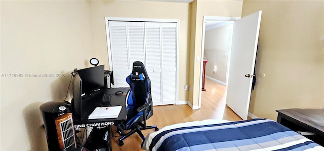 bedroom with a closet, light wood-style flooring, and baseboards