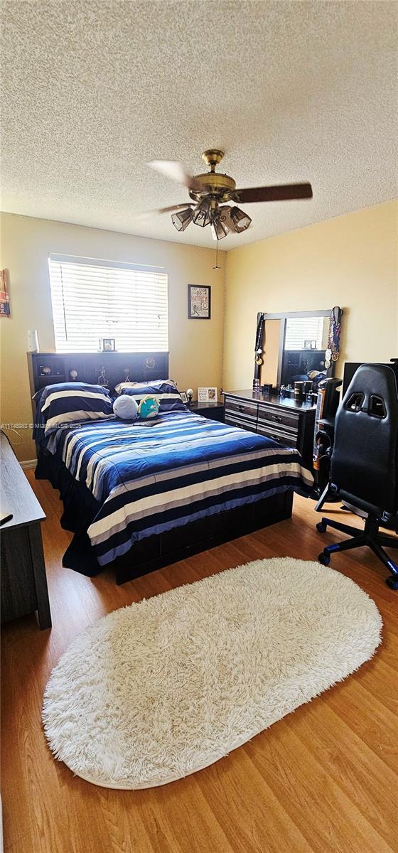18860 NW 12th St, Pembroke Pines, FL 33029 - bedroom featuring wood finished floors, a textured ceiling, and a ceiling fan