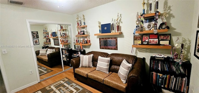 living room featuring a textured ceiling, visible vents, and wood finished floors