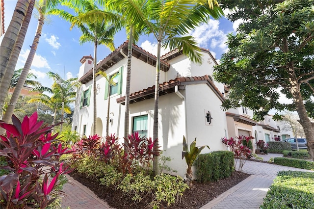 mediterranean / spanish-style house with decorative driveway, an attached garage, a tile roof, and stucco siding