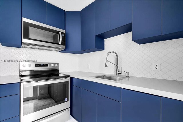 kitchen with appliances with stainless steel finishes, light countertops, a sink, and modern cabinets