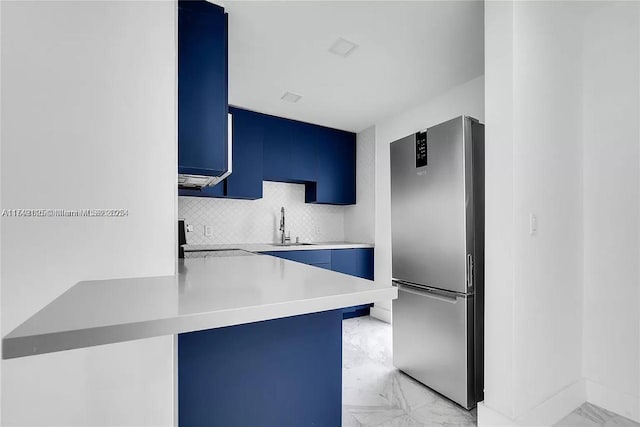 kitchen with marble finish floor, light countertops, stove, freestanding refrigerator, and a peninsula