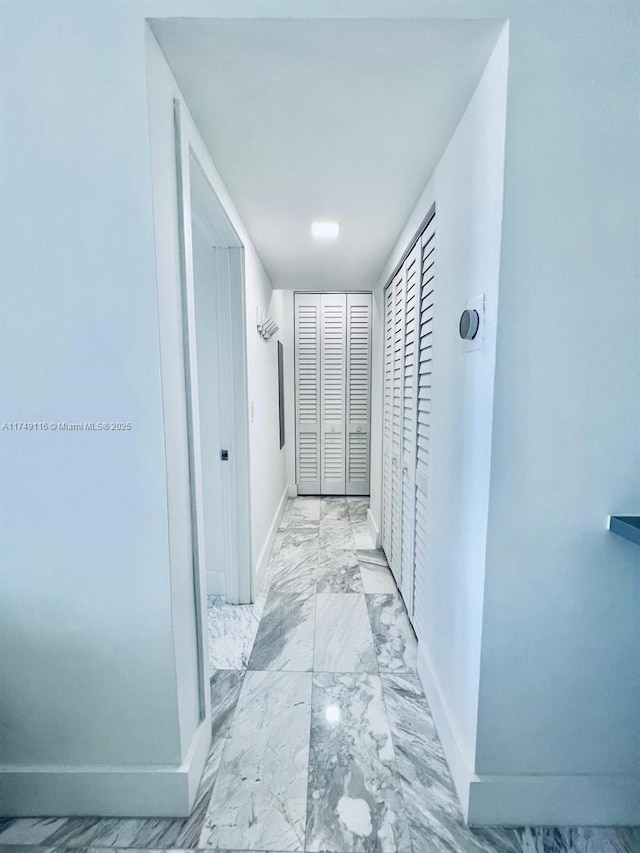 corridor with marble finish floor and baseboards