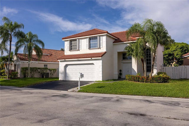 mediterranean / spanish house with fence, driveway, stucco siding, a front lawn, and a tile roof