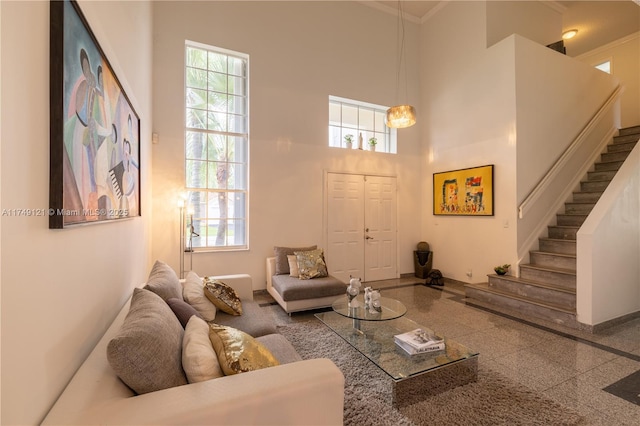 living area featuring a wealth of natural light, stairway, a high ceiling, and granite finish floor