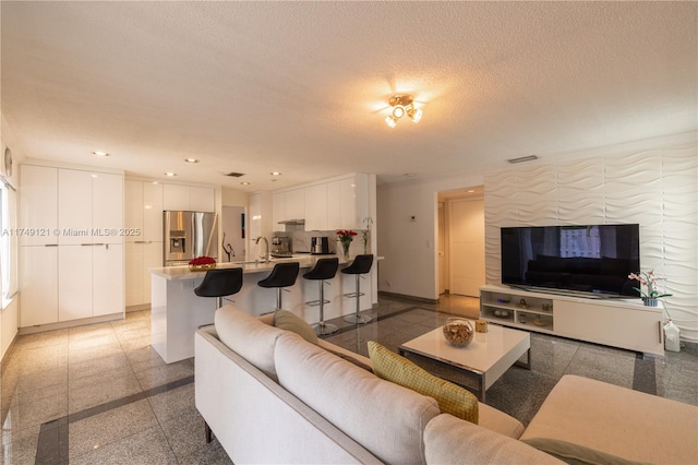 living room with recessed lighting, baseboards, a textured ceiling, and granite finish floor