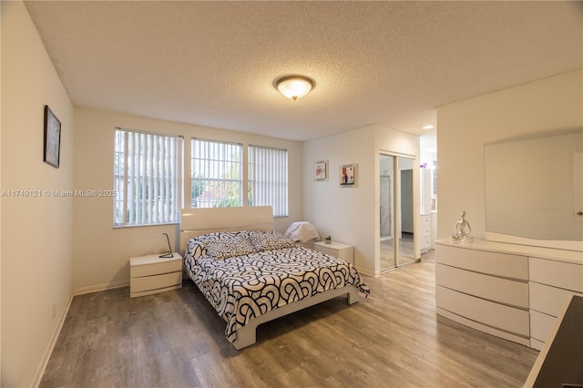 bedroom featuring wood finished floors, baseboards, a closet, and a textured ceiling