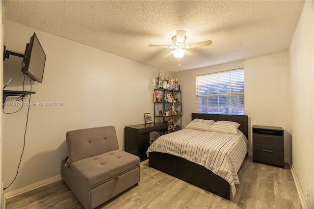 bedroom featuring a textured ceiling, baseboards, ceiling fan, and wood finished floors