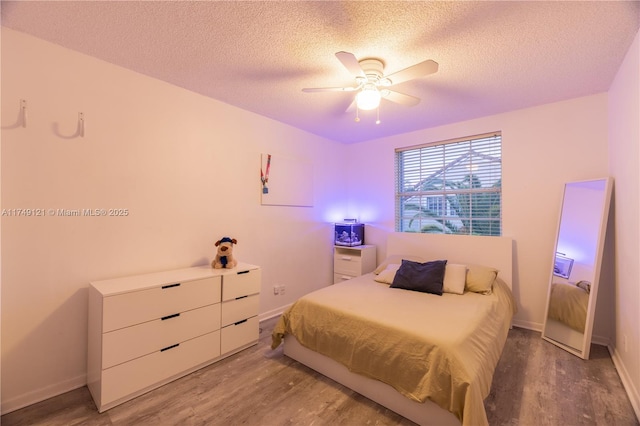 bedroom featuring light wood-style flooring, a ceiling fan, baseboards, and a textured ceiling