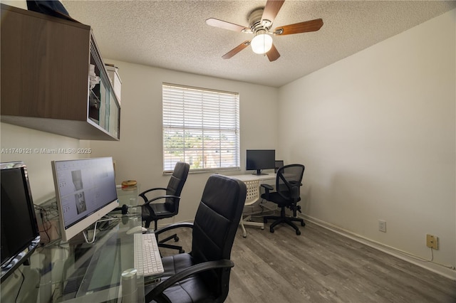 office space with ceiling fan, baseboards, light wood finished floors, and a textured ceiling