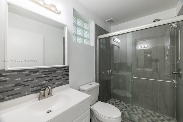 bathroom featuring decorative backsplash, toilet, a stall shower, and vanity