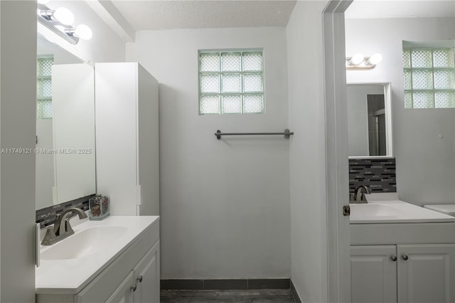 bathroom featuring tasteful backsplash, two vanities, and a sink