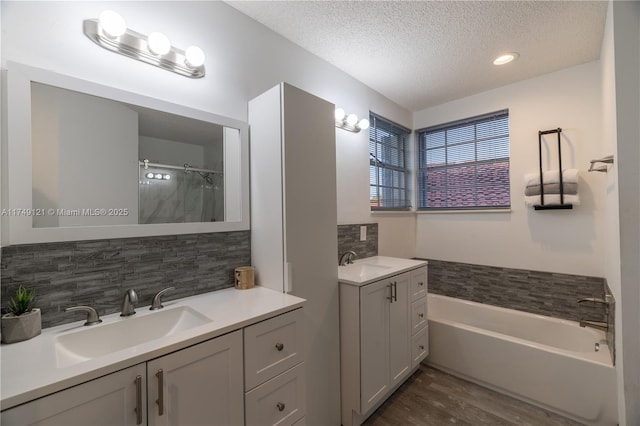 bathroom featuring wood finished floors, a textured ceiling, walk in shower, and a sink