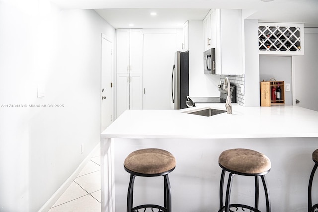 kitchen with stainless steel appliances, light countertops, a peninsula, and a kitchen breakfast bar