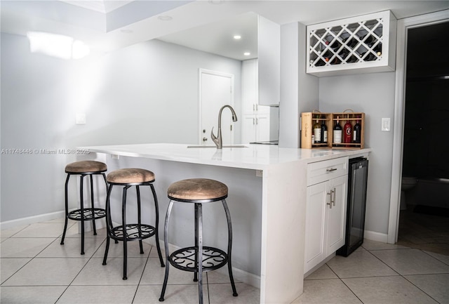 kitchen with a breakfast bar, light countertops, a sink, and white cabinetry