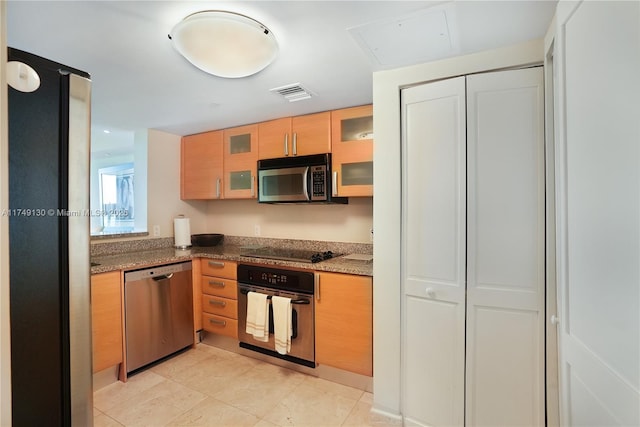 kitchen with light tile patterned floors, visible vents, glass insert cabinets, appliances with stainless steel finishes, and dark stone countertops