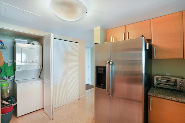 kitchen featuring stacked washer and dryer, light tile patterned flooring, stainless steel fridge, and a toaster