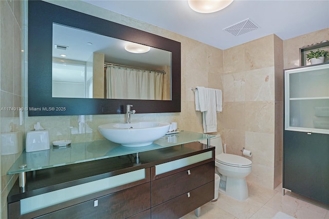 full bath featuring visible vents, tile walls, toilet, and vanity