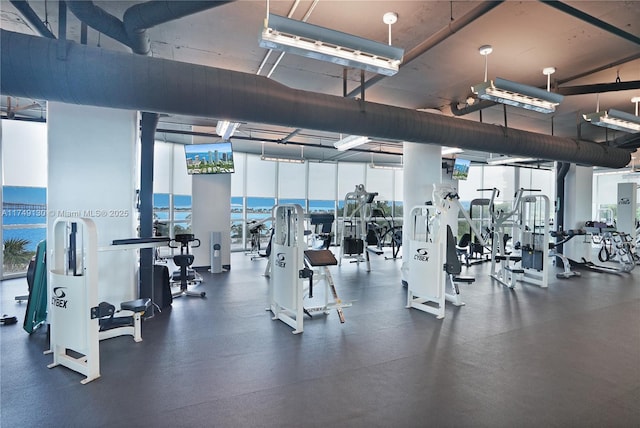 gym featuring floor to ceiling windows, a water view, and plenty of natural light