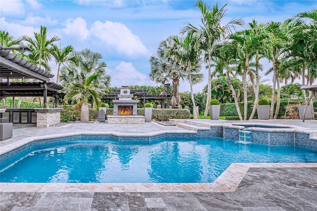 view of swimming pool with a pool with connected hot tub, an outdoor stone fireplace, outdoor dry bar, and a patio