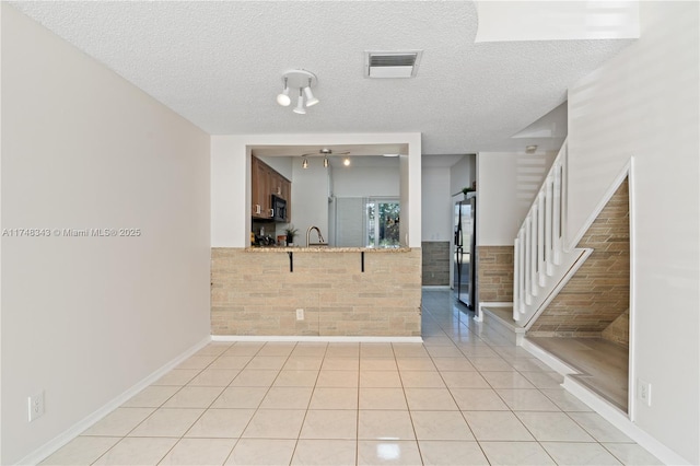 kitchen featuring light countertops, visible vents, light tile patterned flooring, black microwave, and stainless steel fridge