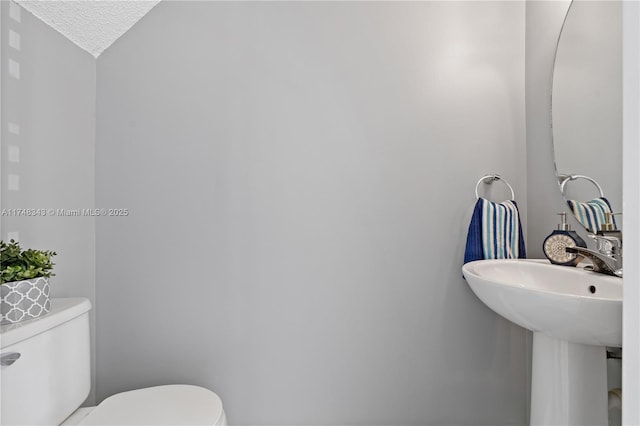 bathroom with a textured ceiling, a sink, and toilet