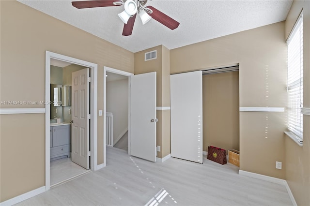 unfurnished bedroom featuring light wood finished floors, a textured ceiling, visible vents, and a closet