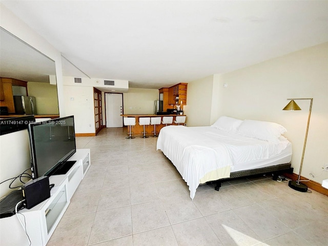 bedroom with visible vents, light tile patterned floors, freestanding refrigerator, and baseboards