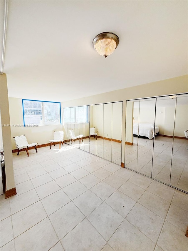 unfurnished bedroom featuring light tile patterned flooring and two closets