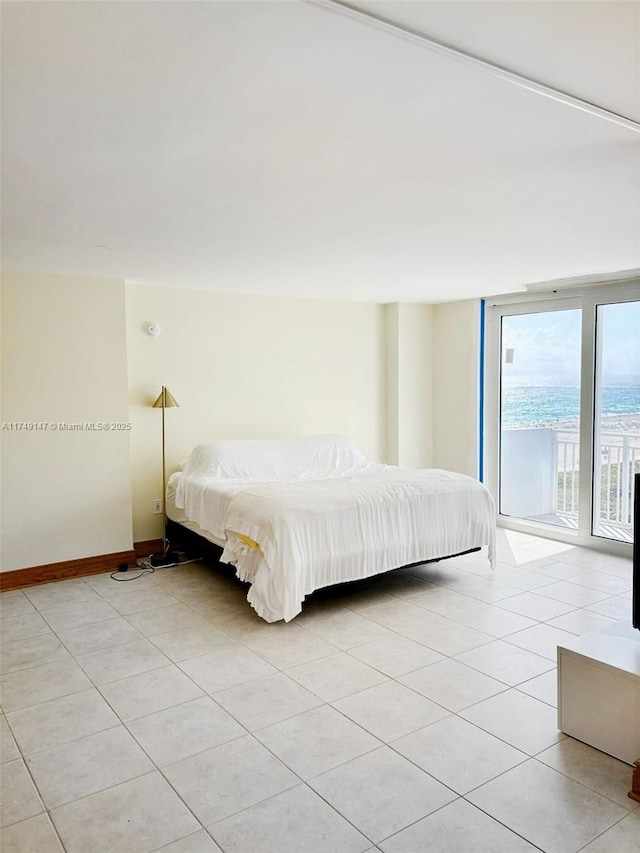 unfurnished bedroom featuring access to outside, floor to ceiling windows, light tile patterned flooring, and baseboards