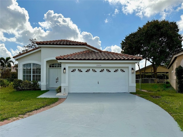 mediterranean / spanish home with fence, concrete driveway, a front yard, stucco siding, and an attached garage