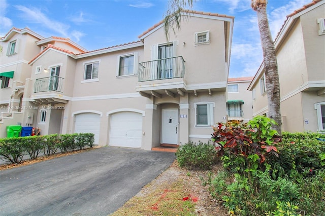 townhome / multi-family property featuring stucco siding, an attached garage, a balcony, driveway, and a tiled roof