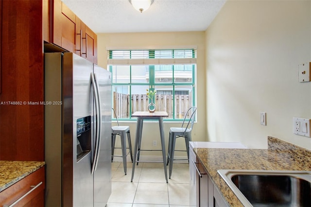 kitchen with light stone counters, a textured ceiling, stainless steel fridge with ice dispenser, and light tile patterned floors