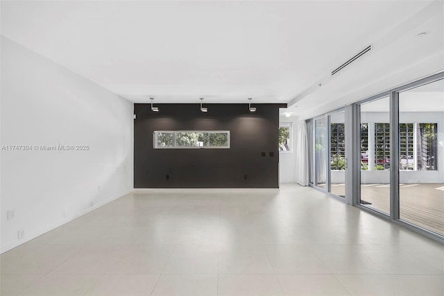 unfurnished room with an accent wall, visible vents, and track lighting