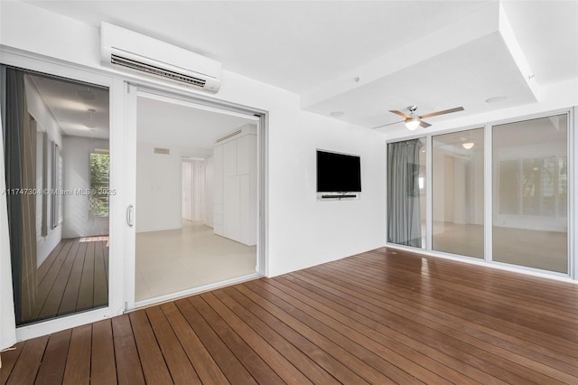 spare room with an AC wall unit, wood finished floors, and a ceiling fan