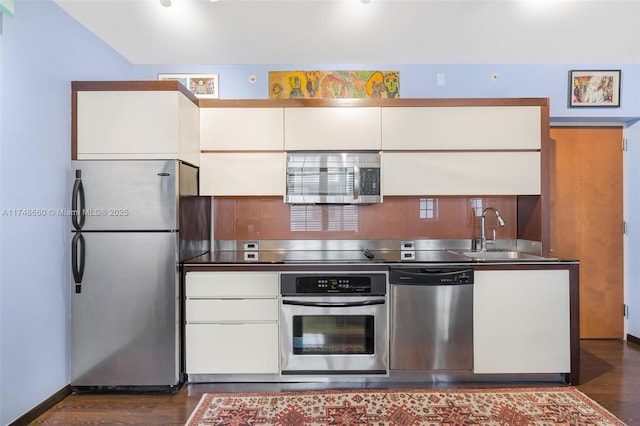 kitchen with stainless steel appliances, dark wood-type flooring, a sink, and white cabinets