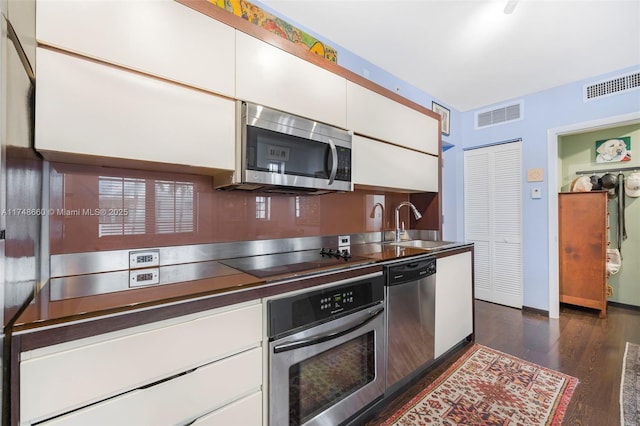 kitchen with stainless steel appliances, white cabinetry, a sink, and visible vents