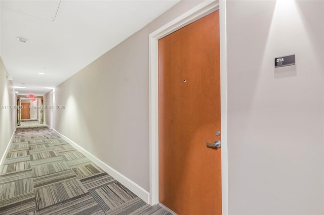 hallway featuring carpet flooring and baseboards