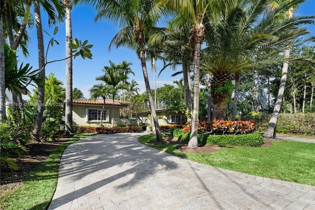 mediterranean / spanish home featuring decorative driveway, a front yard, a tile roof, and stucco siding