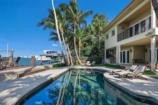 pool featuring area for grilling, a patio, and a water view