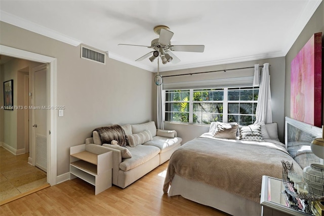 bedroom with baseboards, visible vents, a ceiling fan, ornamental molding, and light wood-style floors