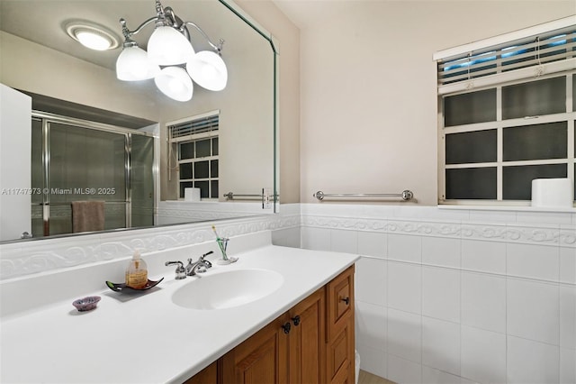 bathroom featuring a stall shower, wainscoting, tile walls, and vanity