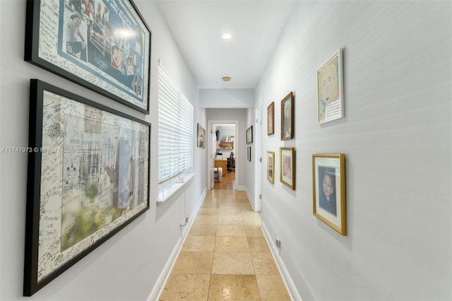 corridor with baseboards and stone tile flooring