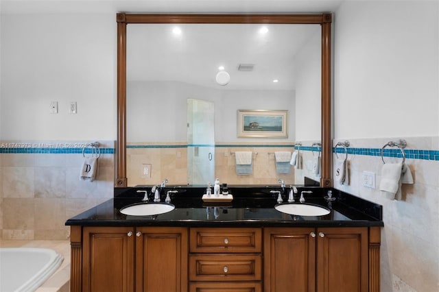 bathroom featuring double vanity, visible vents, tile walls, and a sink