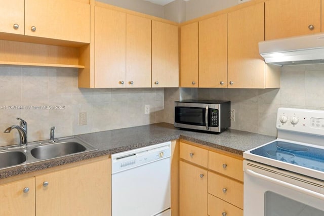 kitchen with a sink, under cabinet range hood, white appliances, dark countertops, and decorative backsplash