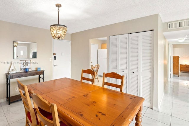 dining room featuring a textured ceiling, visible vents, baseboards, an inviting chandelier, and light tile patterned floors